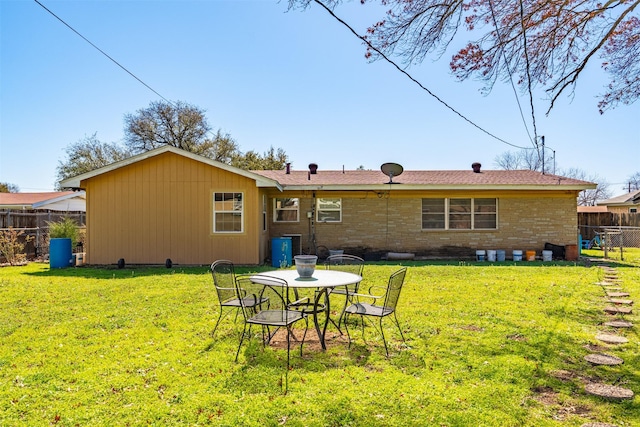 rear view of house featuring a yard and fence