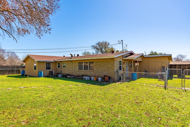 back of property featuring brick siding, fence, cooling unit, a yard, and a gate