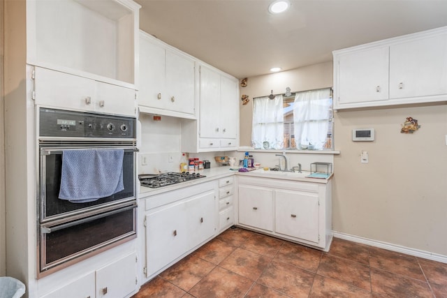 kitchen with a sink, recessed lighting, stainless steel gas stovetop, white cabinets, and light countertops