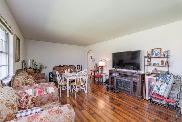 living area featuring arched walkways and wood finished floors