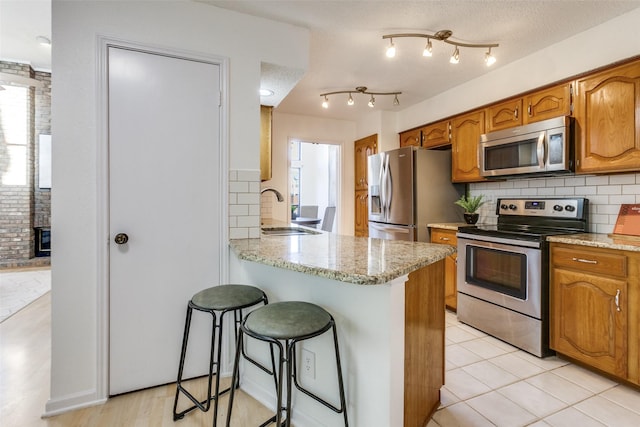 kitchen with a breakfast bar, plenty of natural light, stainless steel appliances, and a sink