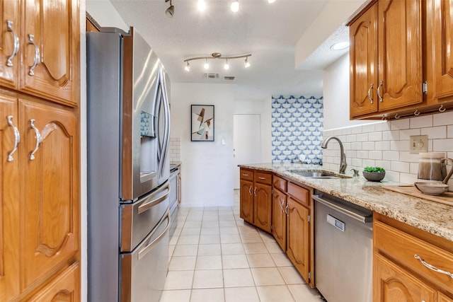 kitchen with backsplash, light tile patterned floors, brown cabinets, appliances with stainless steel finishes, and a sink