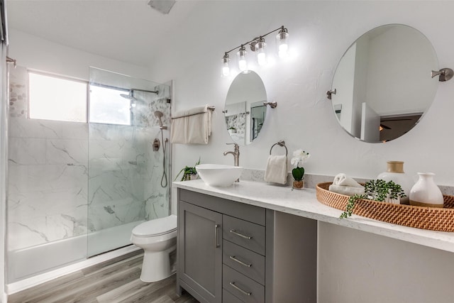 full bath with a marble finish shower, toilet, vanity, and wood finished floors