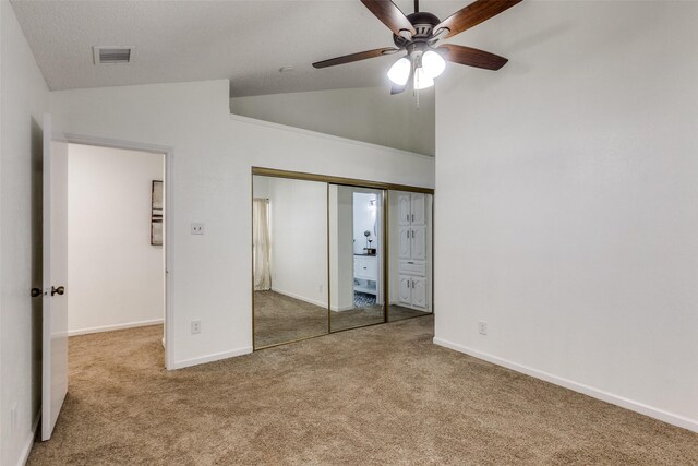 unfurnished bedroom featuring visible vents, a closet, carpet, baseboards, and vaulted ceiling