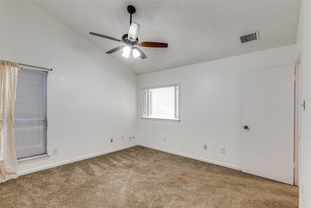 spare room featuring visible vents, vaulted ceiling, carpet flooring, a textured ceiling, and a ceiling fan