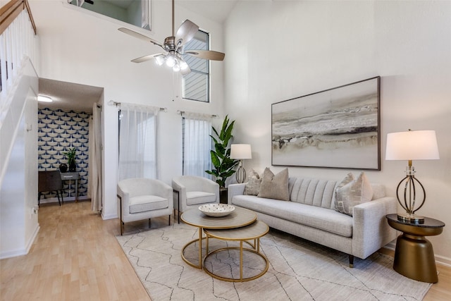 living room featuring a high ceiling, wood finished floors, baseboards, and ceiling fan