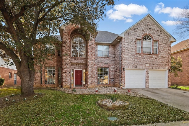 traditional-style house with concrete driveway, a garage, brick siding, and a front yard