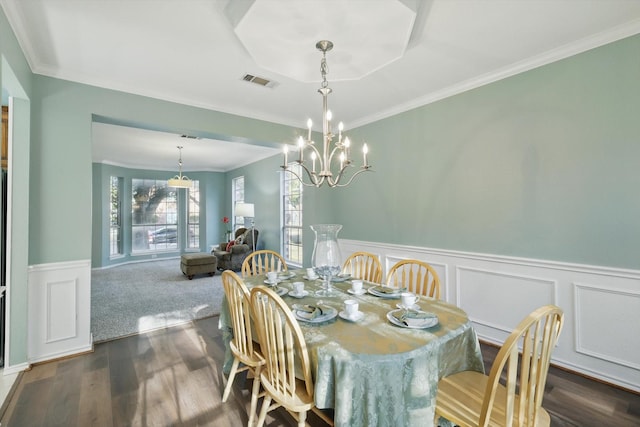 dining room with a wainscoted wall, visible vents, ornamental molding, dark wood-type flooring, and a chandelier