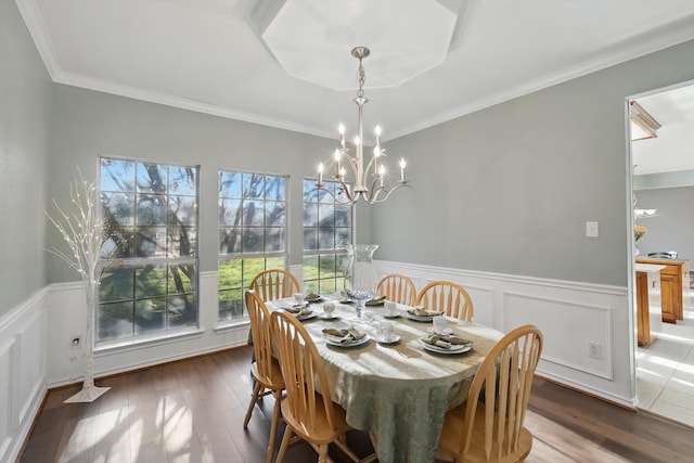 dining area with a wainscoted wall, ornamental molding, an inviting chandelier, and wood finished floors