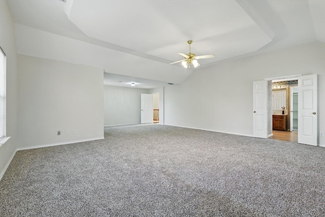 carpeted empty room featuring baseboards, ceiling fan, and vaulted ceiling