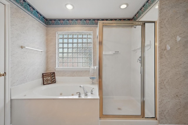 bathroom featuring a shower stall, a tub with jets, and a textured wall