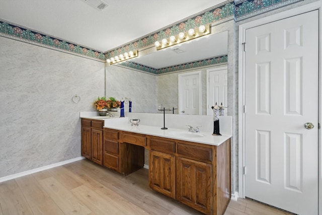 bathroom featuring double vanity, visible vents, wood finished floors, and a sink