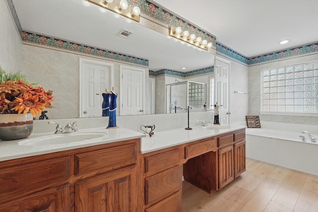 full bath with a sink, a garden tub, double vanity, and a shower stall