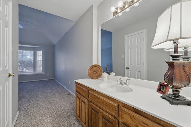 bathroom featuring baseboards, lofted ceiling, and vanity