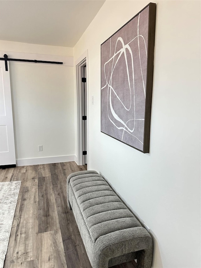 interior space with a barn door, wood finished floors, and baseboards