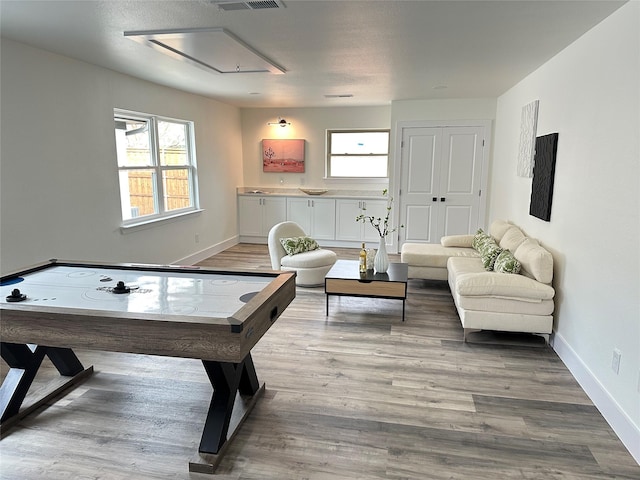 game room with light wood-style flooring, visible vents, and baseboards