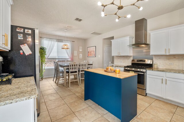 kitchen featuring visible vents, tasteful backsplash, white cabinetry, stainless steel appliances, and wall chimney exhaust hood