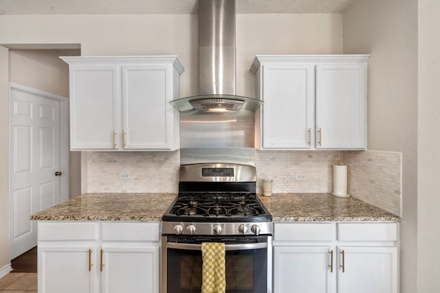 kitchen featuring stainless steel gas range oven, light stone countertops, wall chimney exhaust hood, and white cabinetry