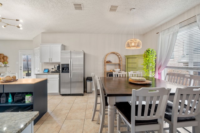 kitchen featuring visible vents, light countertops, light tile patterned floors, stainless steel refrigerator with ice dispenser, and white cabinetry