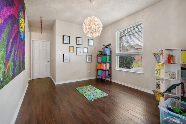 playroom featuring a textured ceiling, baseboards, and wood-type flooring