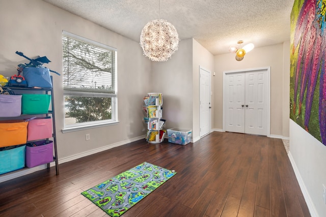 foyer entrance with baseboards, a textured ceiling, a chandelier, and hardwood / wood-style flooring