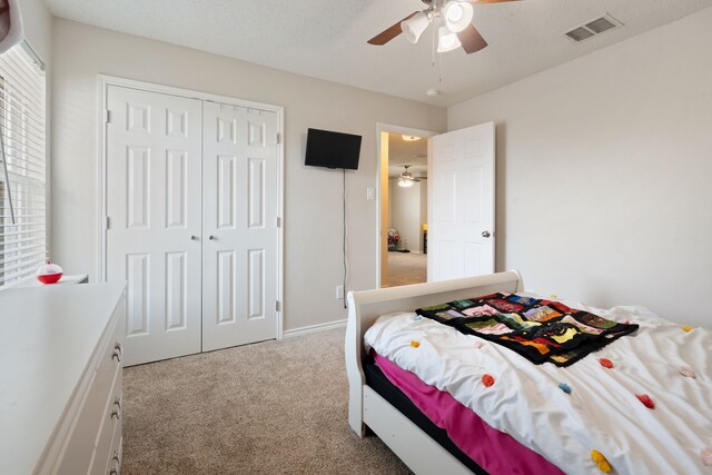 bedroom featuring visible vents, ceiling fan, light colored carpet, a closet, and a textured ceiling