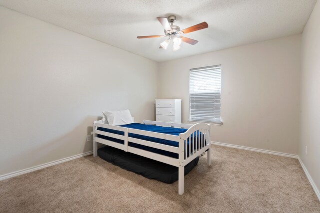 bedroom with ceiling fan, baseboards, carpet floors, and a textured ceiling