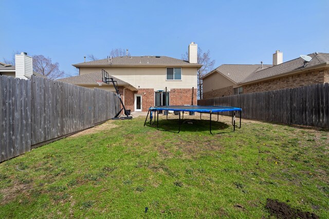 view of yard featuring a trampoline and a fenced backyard