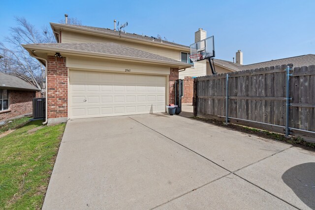 exterior space featuring concrete driveway, central air condition unit, fence, and brick siding