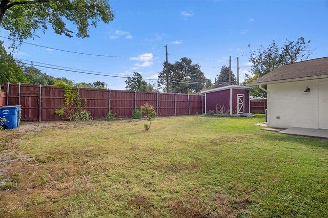 view of yard featuring an outdoor structure, a fenced backyard, and a shed