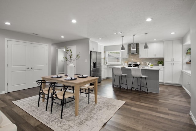 dining room with dark wood-style floors, recessed lighting, a textured ceiling, and baseboards