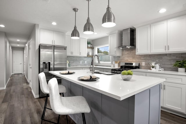 kitchen with white cabinets, stainless steel appliances, wall chimney exhaust hood, and light countertops