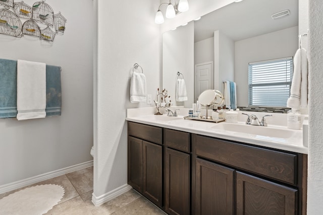 bathroom with tile patterned flooring, double vanity, baseboards, and a sink