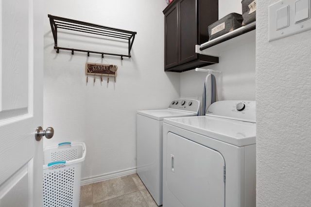 laundry area featuring light tile patterned floors, cabinet space, baseboards, and washing machine and clothes dryer