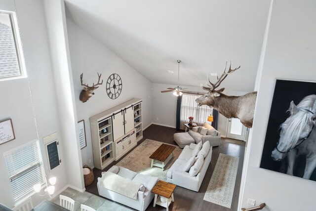 living area with high vaulted ceiling, wood finished floors, baseboards, and ceiling fan