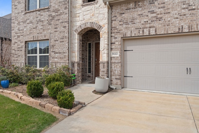 property entrance with concrete driveway, a garage, and brick siding