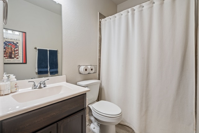 full bathroom featuring vanity, curtained shower, toilet, and a textured wall