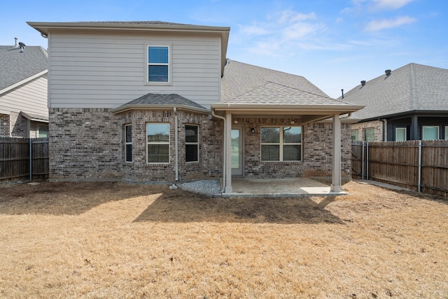 back of house with brick siding, a patio area, a shingled roof, and a fenced backyard