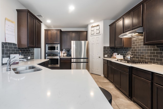 kitchen featuring visible vents, under cabinet range hood, light tile patterned floors, stainless steel appliances, and a sink