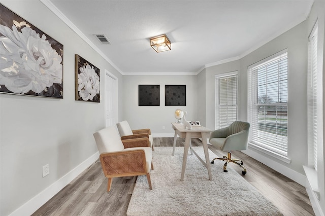 living area featuring visible vents, baseboards, wood finished floors, and crown molding