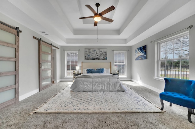 bedroom featuring a barn door, carpet floors, a raised ceiling, baseboards, and visible vents