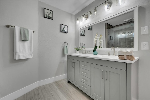 bathroom with a shower stall, baseboards, a sink, and double vanity