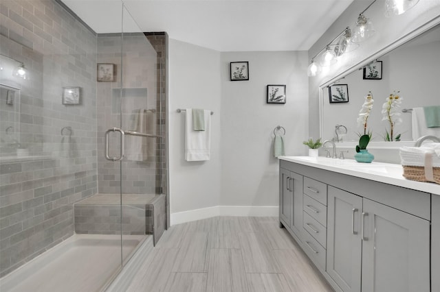 full bathroom featuring a shower stall, baseboards, a sink, and double vanity