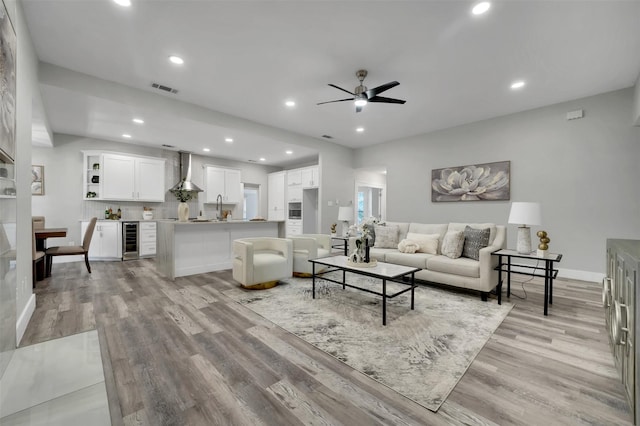 living area featuring light wood-style floors, ceiling fan, wine cooler, visible vents, and recessed lighting