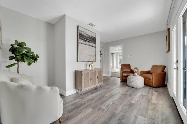 sitting room with baseboards, light wood-style floors, and visible vents