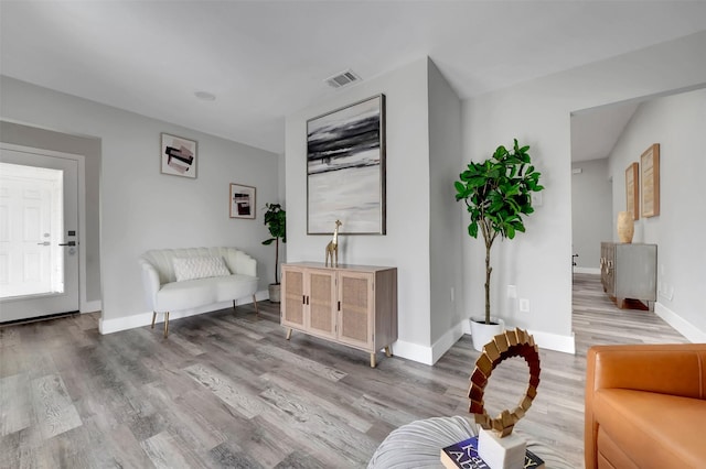living area with baseboards, wood finished floors, and visible vents
