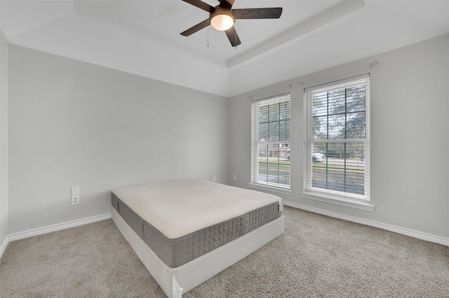 bedroom with a tray ceiling, carpet floors, baseboards, and ceiling fan
