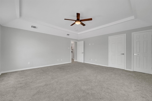 unfurnished room with a tray ceiling, visible vents, baseboards, a ceiling fan, and carpet floors