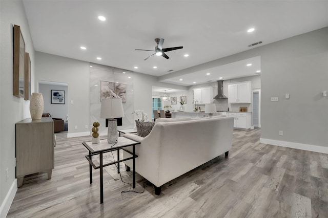 living area featuring light wood-type flooring, ceiling fan, baseboards, visible vents, and recessed lighting