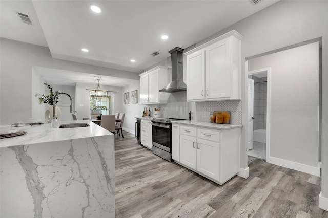 kitchen featuring wall chimney range hood, a sink, light wood-style floors, stainless steel electric range oven, and visible vents